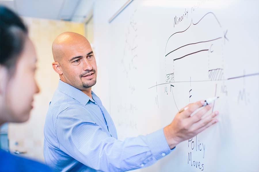 faculty memeber writing on the whiteboard teaching students